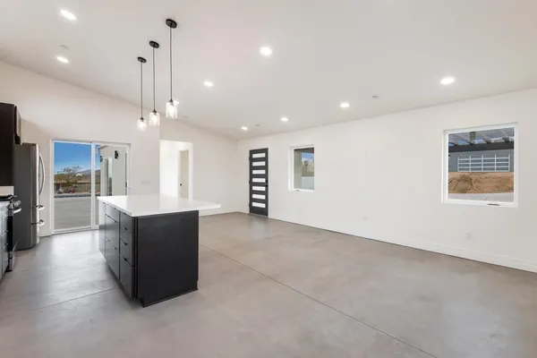 a large kitchen with stainless steel appliances kitchen island granite countertop a refrigerator a sink a stove and oven with wooden floor