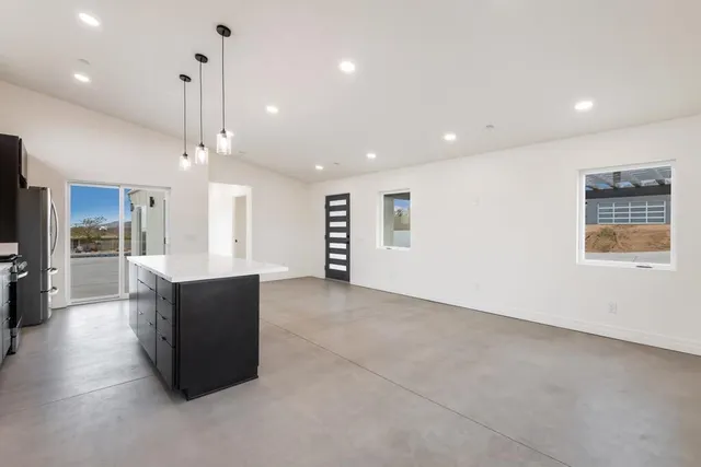 a large kitchen with stainless steel appliances kitchen island granite countertop a refrigerator a sink a stove and oven with wooden floor