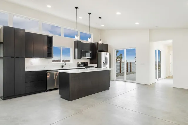 a view of a kitchen with a sink and dishwasher a stove top oven with wooden floor