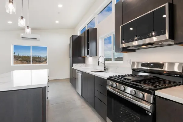 a view of kitchen with stainless steel appliances kitchen island granite countertop a stove top oven a sink a counter top space and cabinets