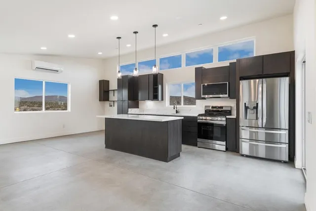 a kitchen with stainless steel appliances a refrigerator a stove a sink a center island and chairs