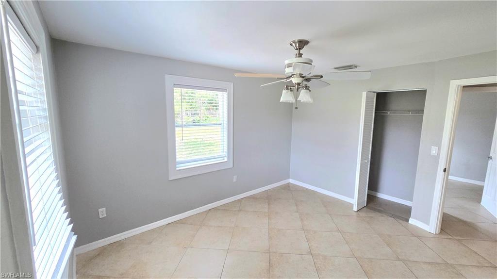 5529 Hardee Street Naples, FL 34113 - Photo 11 of 17 Bedroom #3 featuring light gray walls, tile flooring, a window with horizontal blinds, a ceiling fan with integrated lighting, and an open closet with shelving