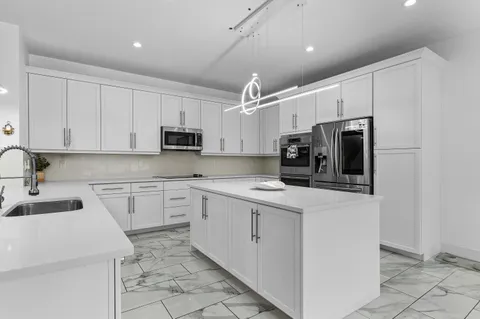 a kitchen with kitchen island a stove a table and chairs