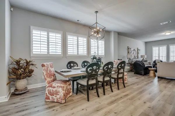 a view of a dining room and livingroom with furniture wooden floor a chandelier