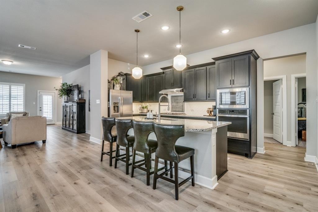 1268 Caprock Drive Forney, TX 75126 - Photo 16 of 35 a kitchen with stainless steel appliances kitchen island granite countertop a refrigerator and a stove top oven