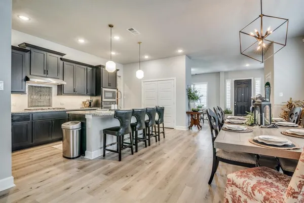 a kitchen with a dining table chairs stainless steel appliances and cabinets