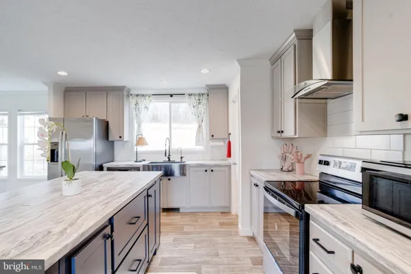 a kitchen with a stove a sink a refrigerator and white cabinets with wooden floor