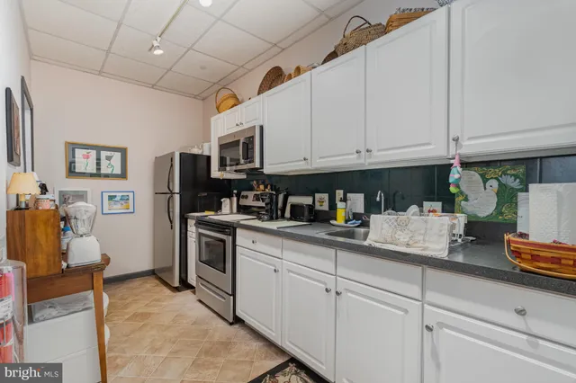 a kitchen with granite countertop a sink stainless steel appliances and white cabinets