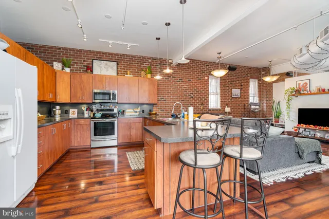 a kitchen with stainless steel appliances kitchen island granite countertop a table chairs and a refrigerator