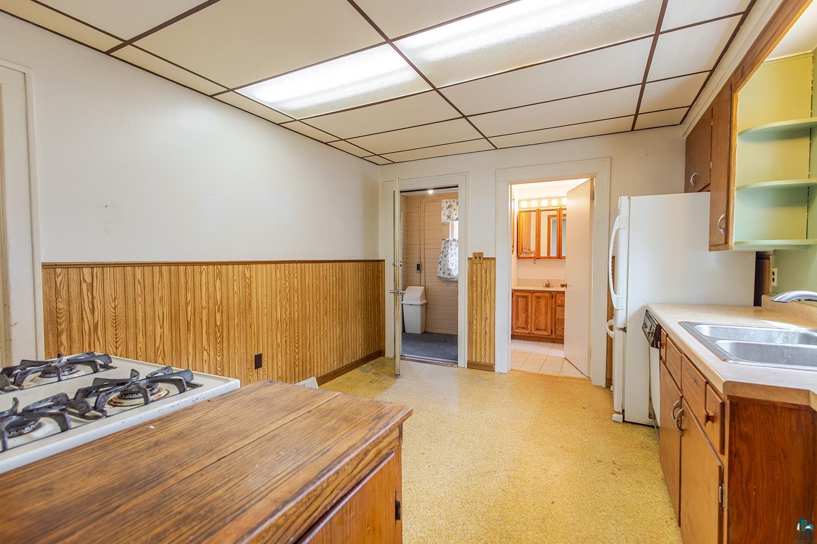438 9th Street Cloquet, MN 55720 - Photo 11 of 27 Kitchen featuring wood-paneled wainscoting, space for table, recessed lighting, and a dual basin sink