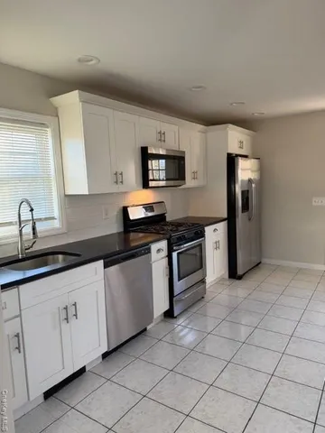 a kitchen with granite countertop white cabinets and stainless steel appliances