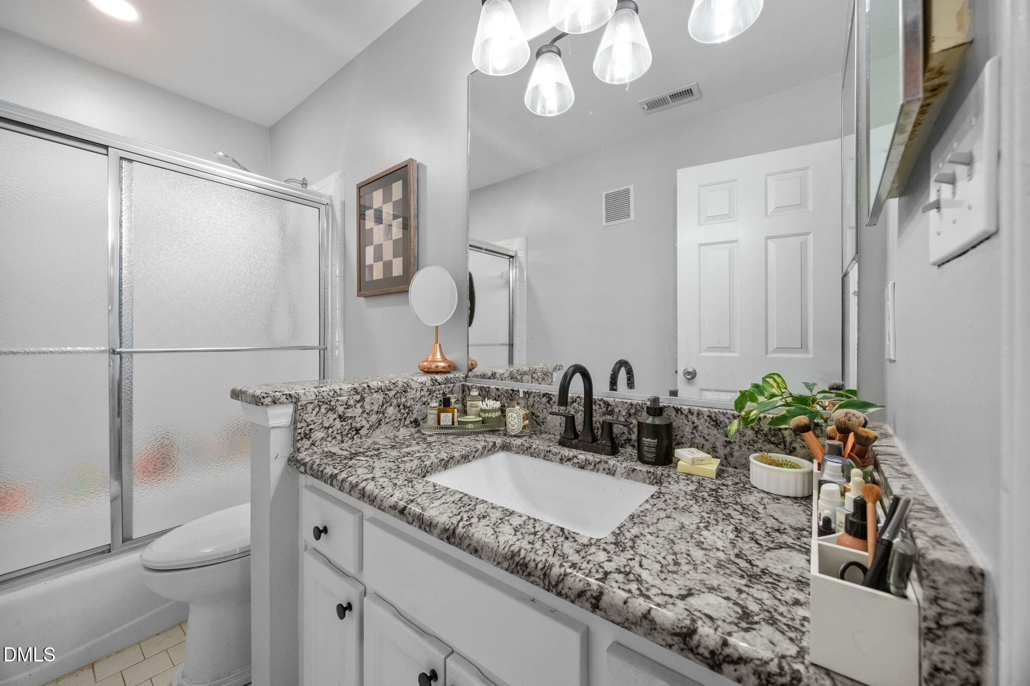 1021 Brighthurst Drive, Unit 103 Raleigh, NC 27605 - Photo 12 of 27 a bathroom with a granite countertop sink a mirror and a shower