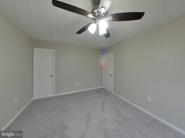 an empty room with a chandelier fan and windows