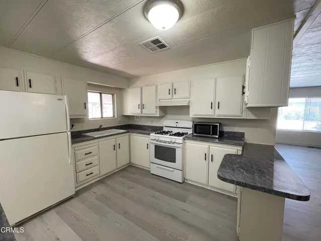 a kitchen with granite countertop white cabinets and white appliances