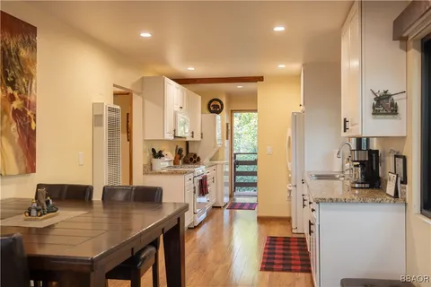 a view of a kitchen with kitchen island granite countertop a refrigerator and cabinets