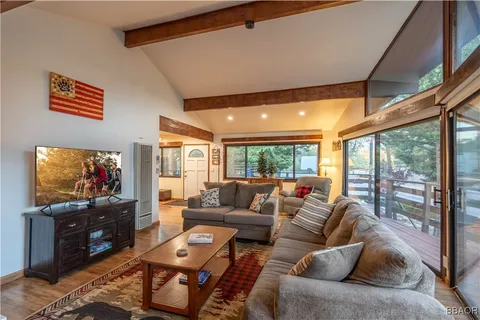 a living room with furniture a flat screen tv and a floor to ceiling window