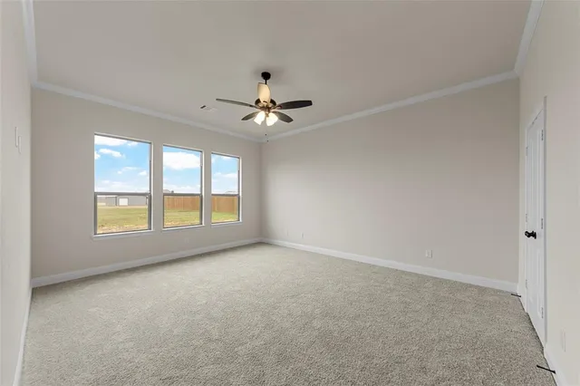 an empty room with chandelier fan and windows