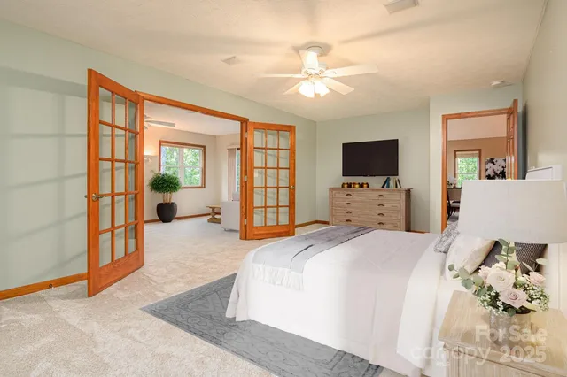 a spacious bedroom with a large bed and a flat tv screen