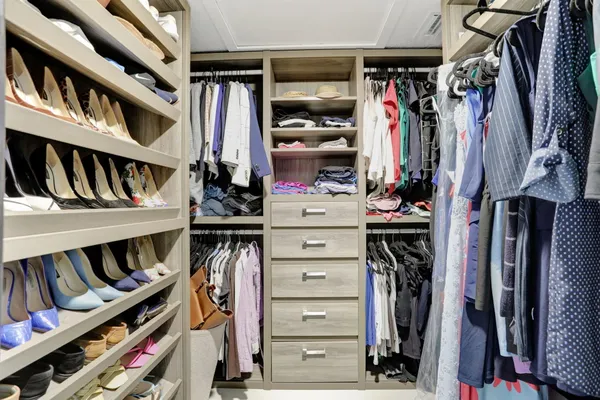 a view of walk in closet with clothes and shoes