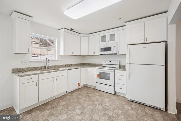 a kitchen with granite countertop white cabinets and white appliances