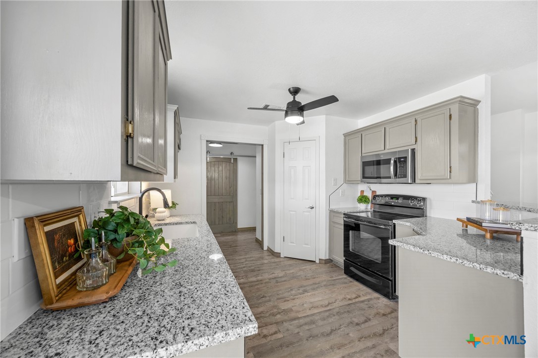5107 Denmans Loop Belton, TX 76513 - Photo 12 of 48 a kitchen with stainless steel appliances granite countertop a stove top oven a sink a refrigerator and white cabinets with wooden floor
