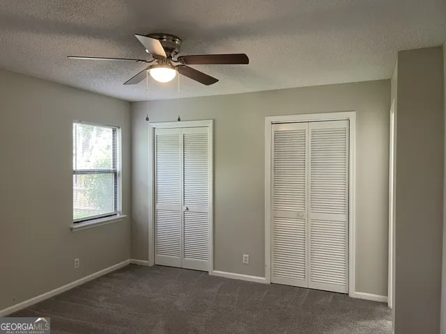 an empty room with windows and fan