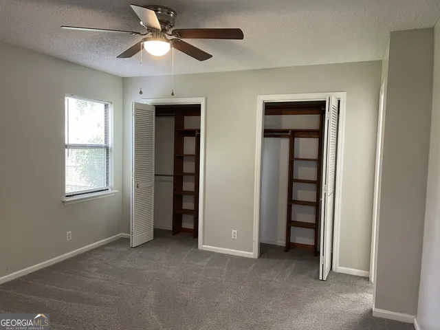 an empty room with closet and a ceiling fan