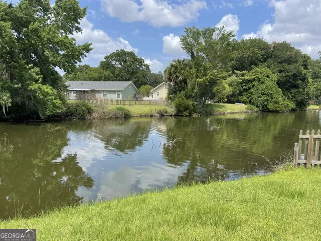 a view of a lake with a yard and large trees