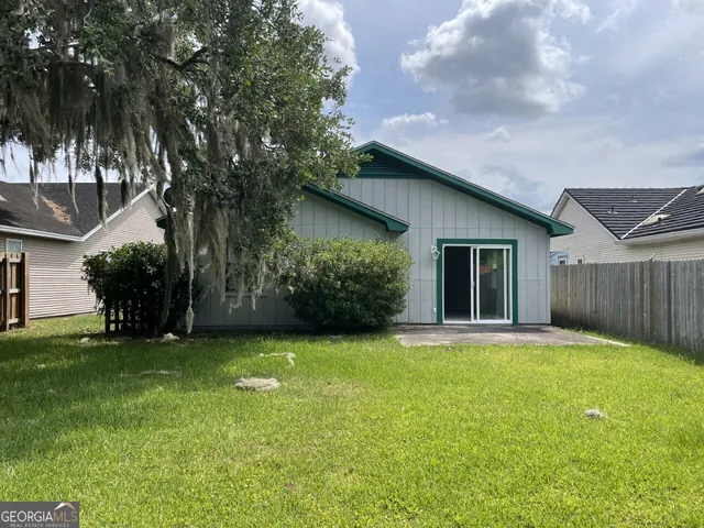 a backyard of a house with plants and large trees