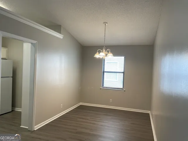 an empty room with wooden floor chandelier and window