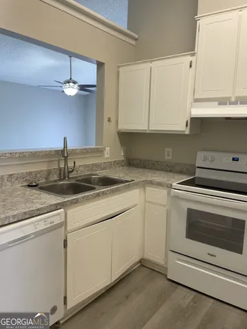 a kitchen with granite countertop white cabinets white stainless steel appliances and a sink