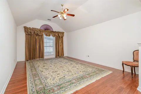 a view of a hallway with wooden floor and a ceiling fan