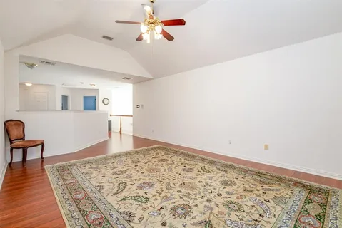 a view of a bedroom with wooden floor and ceiling fan