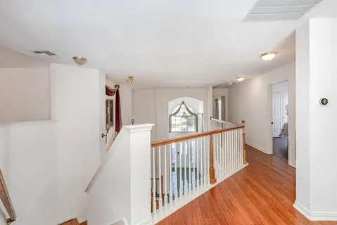 a view of a hallway to a livingroom with wooden floor and stairs