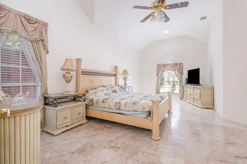 a spacious bedroom with a bed and a flat tv screen on the dresser