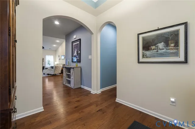 a view of a hallway with wooden floor and a kitchen