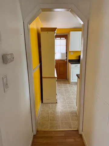 a view of a hallway with wooden floor and a bathroom