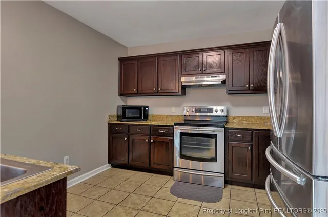 a kitchen with stainless steel appliances granite countertop a stove a refrigerator and a sink