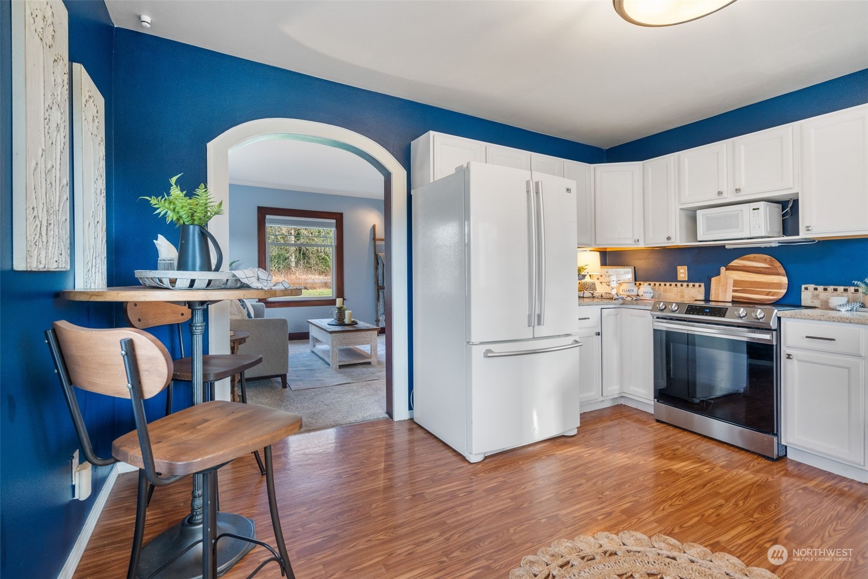 2628 Old Highway 99 North Road Burlington, WA 98233 - Photo 10 of 40 a kitchen with stainless steel appliances a refrigerator a stove a sink a dining table and chairs with wooden floor