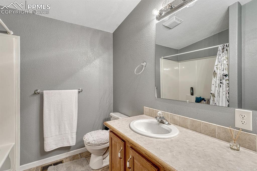 15371 Buck Creek Road Elbert, CO 80106 - Photo 19 of 50 a bathroom with a granite countertop sink a toilet and a mirror