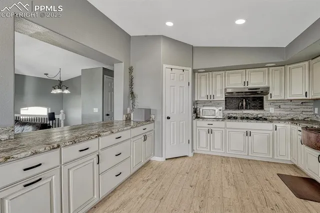 a dining room filled chandelier and kitchen view