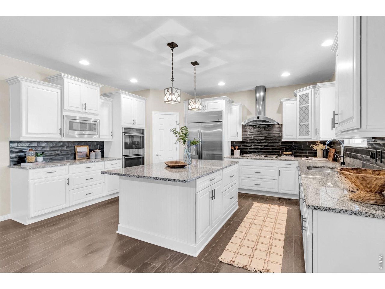 6028 Moran Road Timnath, CO 80547 - Photo 1 of 49 a kitchen with stainless steel appliances granite countertop a stove top oven a sink a refrigerator and white cabinets with wooden floor