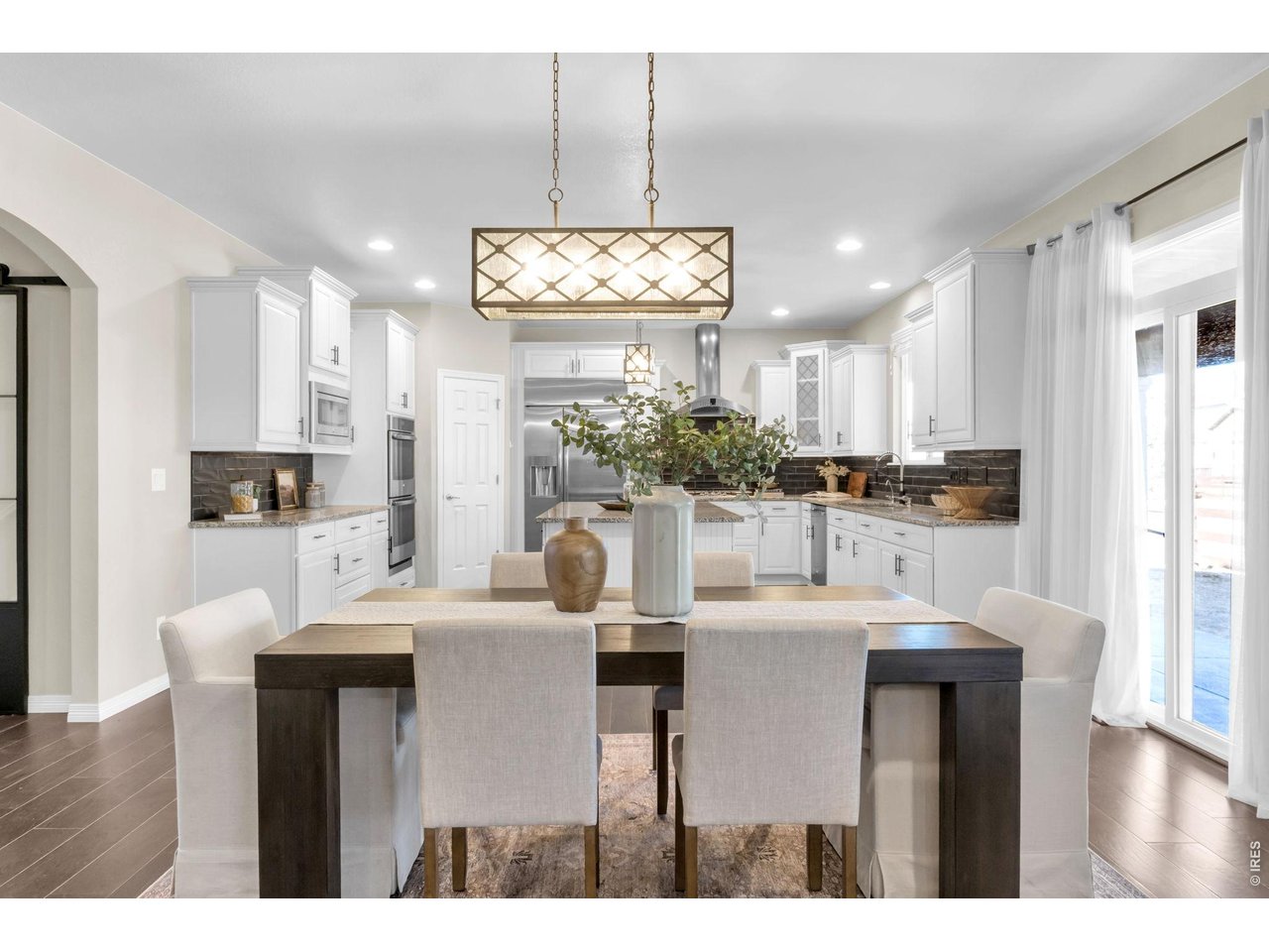 6028 Moran Road Timnath, CO 80547 - Photo 14 of 49 a kitchen with stainless steel appliances kitchen island granite countertop a refrigerator a stove and white cabinets with wooden floor