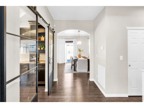 a kitchen with stainless steel appliances granite countertop a stove top oven a sink a refrigerator and white cabinets with wooden floor