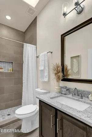 a bathroom with a granite countertop sink mirror vanity and toilet