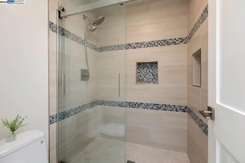 a bedroom with bed a mirror and a large window