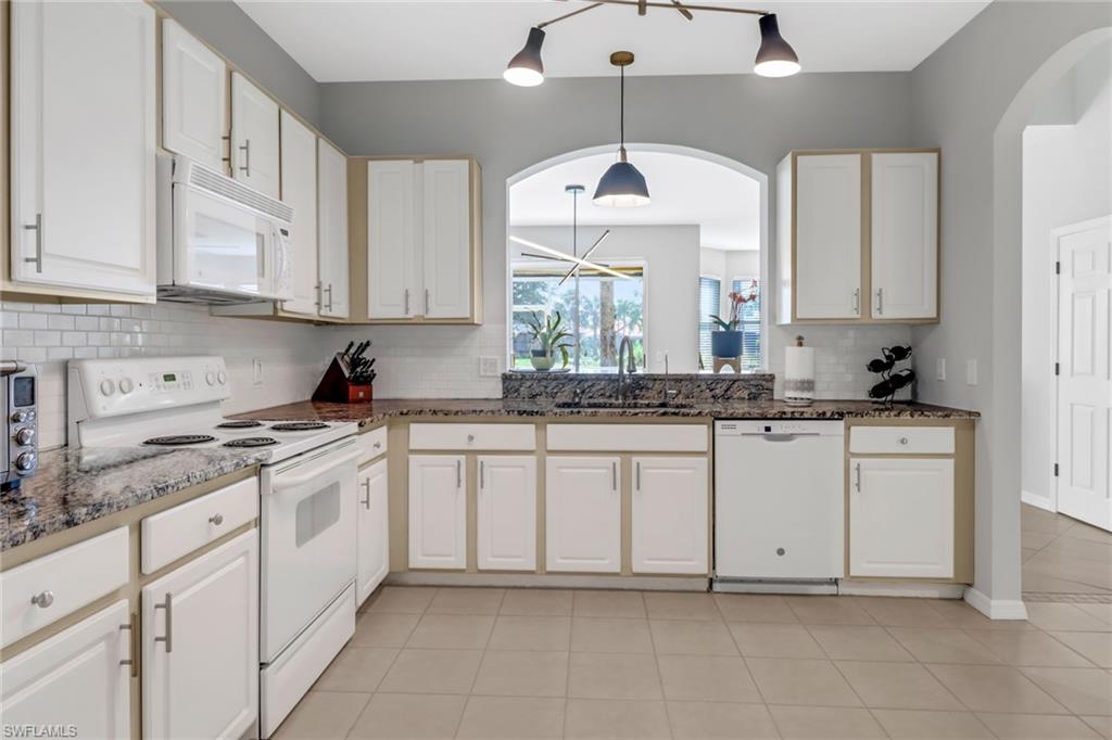 20024 Heatherstone Way, Unit 2 Estero, FL 33928 - Photo 4 of 38 a kitchen with granite countertop white cabinets white appliances with a sink and dishwasher