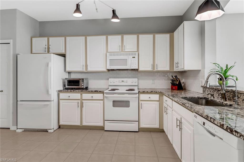20024 Heatherstone Way, Unit 2 Estero, FL 33928 - Photo 5 of 38 a kitchen with white cabinets and white appliances