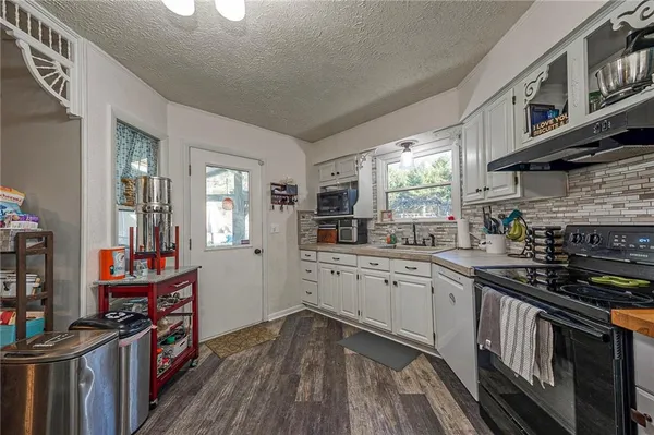 a kitchen with granite countertop a stove top oven sink and cabinets