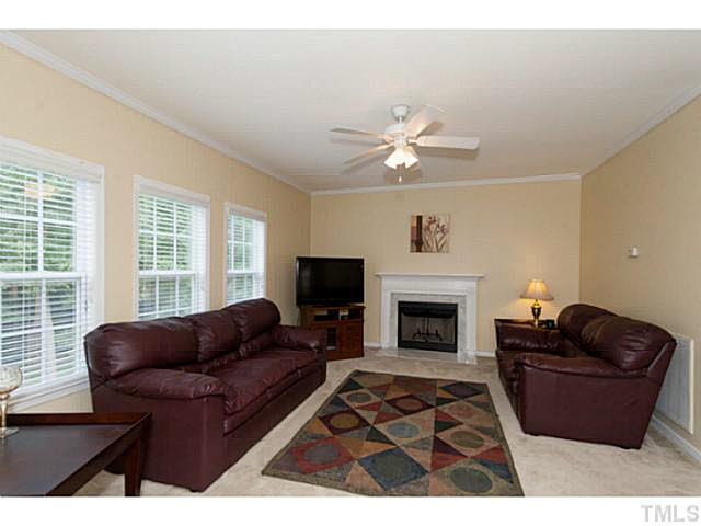 8424 Ridgebury Road Raleigh, NC 27603 - Photo 9 of 25 a living room with furniture a fireplace and a large window